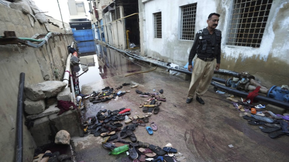 En polis på platsen i Karachi där minst elva personer trampades ihjäl.
