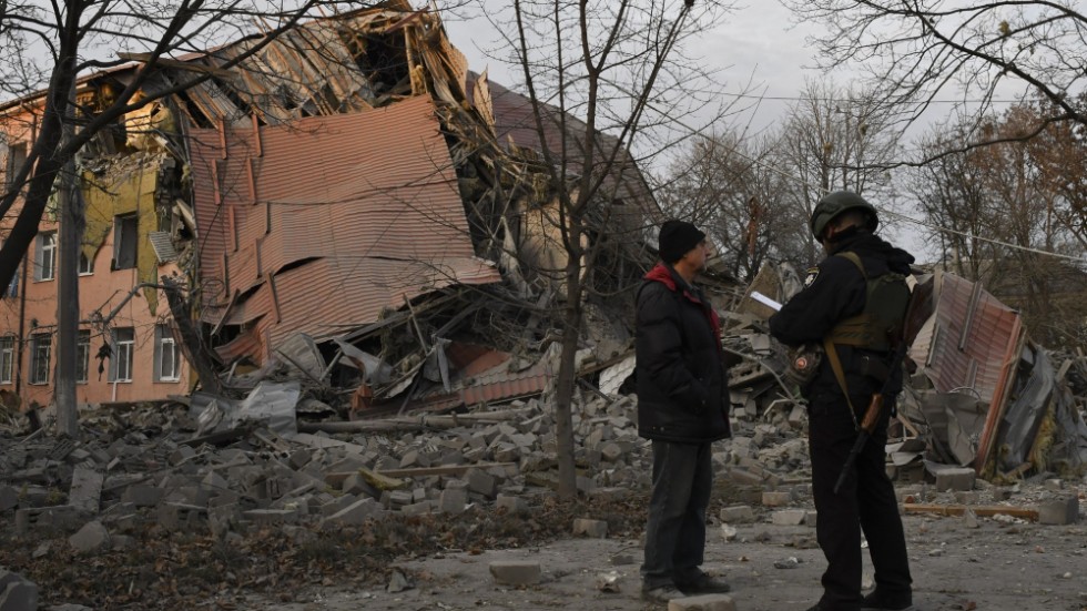 En polis och en man står framför en skola i Kramatorsk som förstörts i en rysk attack. Arkivbild.