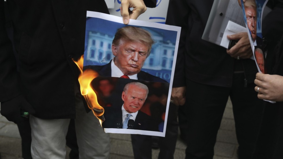 Demonstranter i Iran bränner en bild på USA:s nuvarande president Donald Trump och den tillträdande presidenten Joe Biden efter mordet på Mohsen Fakhrizadeh i Iran. USA:s allierade Israel har av Iran pekats ut som skyldig till mordet.
