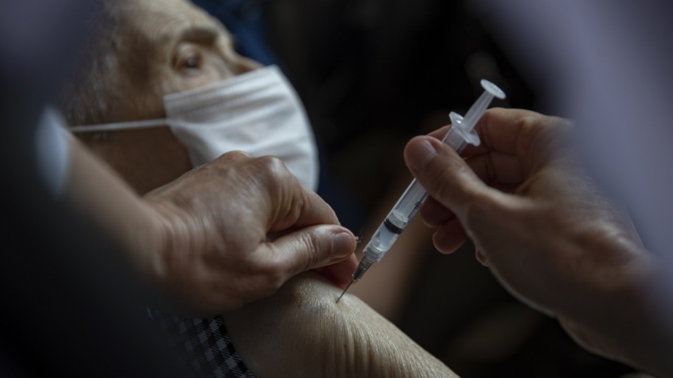 En vårdarbetare i Brasilien vaccinerar en äldre man med Sinovac.