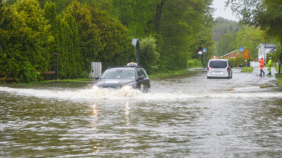 Trafik på översvämmad gata i Huddinge efter det kraftiga regnandet.