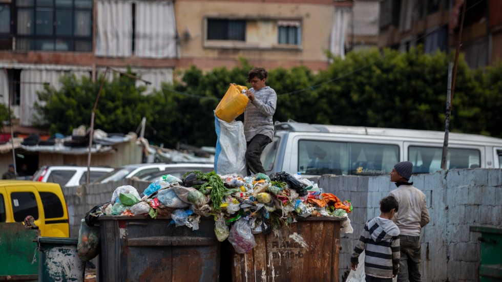 Barn letar efter något av värde i soporna bredvid en marknad i Beirut.