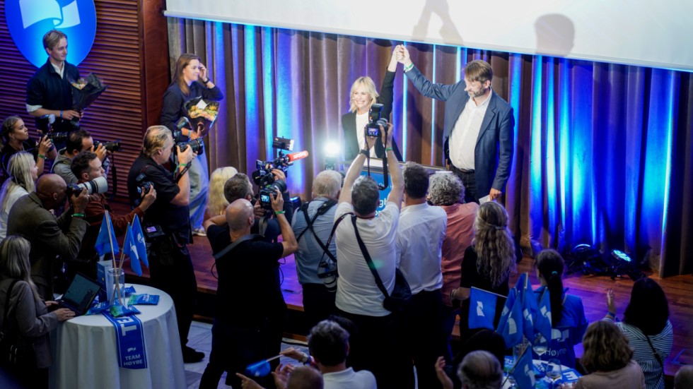Eirik Lae Solberg och Anne Lindboe höjer varandras händer på Høyres valvaka i Oslo på måndagskvällen.