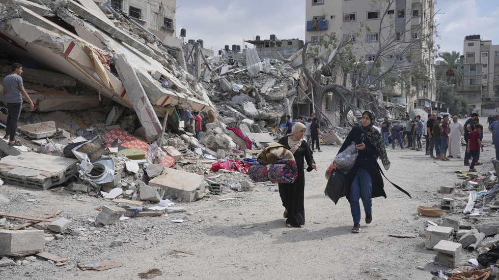 Palestinska kvinnor går förbi rester av bostadshus i Nuseirat i centrala Gaza. Bilden togs i oktober, tio dagar in i kriget mellan Israel och Hamas.