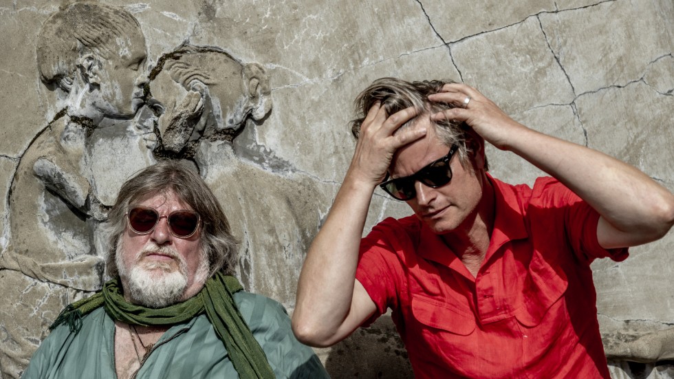 Ebbot Lundberg och Martin Hederos minns turnerandet med Oasis, sittande vid en betongtavla av konstnären Lui Hopf utanför replokalen i Göteborg.