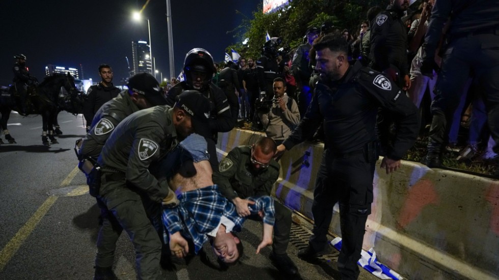Israelisk polis flyttar på demonstranter som blockerar en motorväg invid Tel Aviv under en protest mot den israeliska regerings planer på att förändra rättsväsendet.