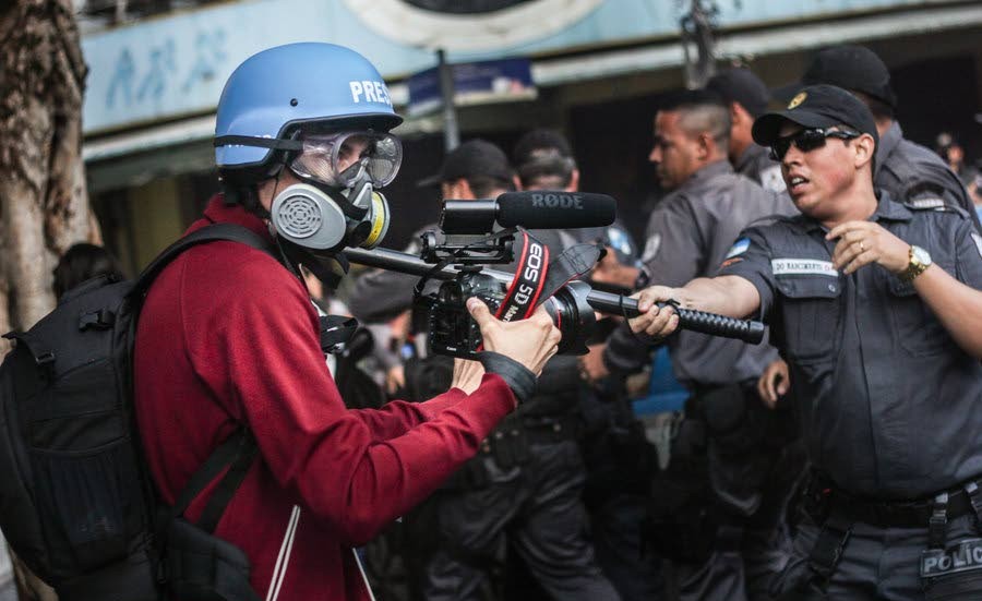En militärpolis slår en reporter under finaldagens protester nära Maracana.
