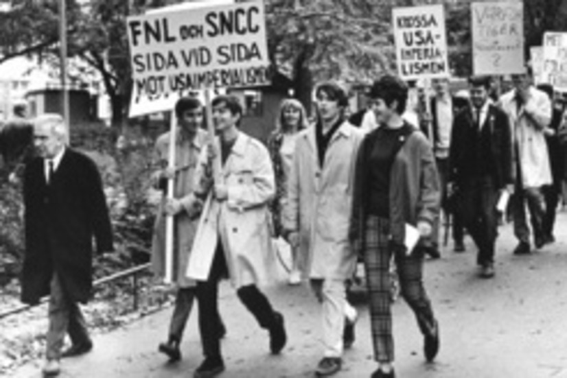 FNL-rörelsen. Scanpix ursprungliga bildtext från en FNL-demonstration den 21/10 1967 lyder "Glada ungdomar med plakat - Krossa USA:s imperialism - går med raska steg förbi en äldre man på vägen".