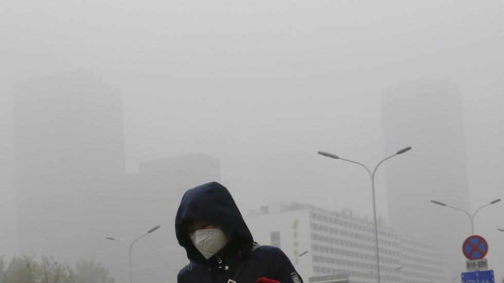En kvinna skyddar sig mot föroreningar genom att använda munskydd i Peking. Bilden är från 2018.