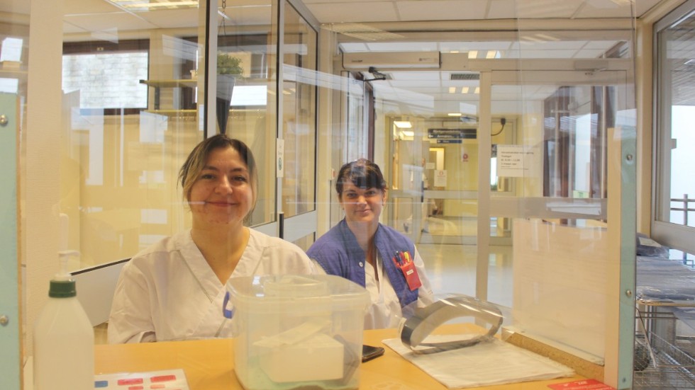 Dörrvärdarna Suzan Badr (till vänster) och Frida Grönvall sitter i hälsocentralens entré för att kontrollera att bara personer fria från förkylningssymptom kommer in. 