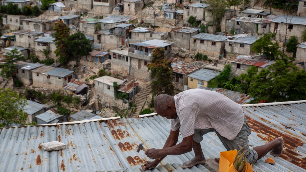 En man i Port-au-Prince i Haiti, stormsäkrar sitt hus i väntan på det tropiska ovädret Elsa.