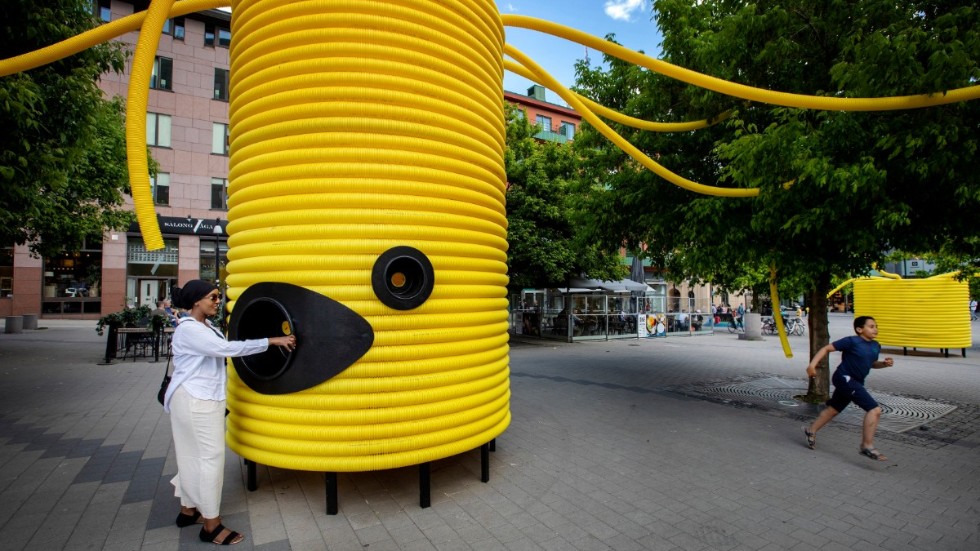 Det interaktiva verket ”Hej främling” av den italiensk-portugisiska gruppen Moradavaga är stora gula figurer av ihopsatta rör som sveper över sittplatser och träd på ett av Örebros torg. Pressbild.