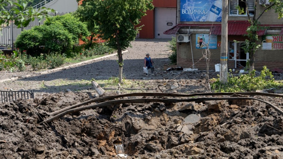 En kvinna i staden Bachmut i Donetskregionen tittar på kratern som orsakats av en rysk raket. Bild från 1 juli.