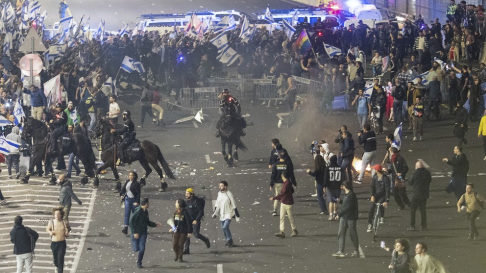 Israelisk polis skingrar demonstranter på en huvudgata i Tel Aviv.