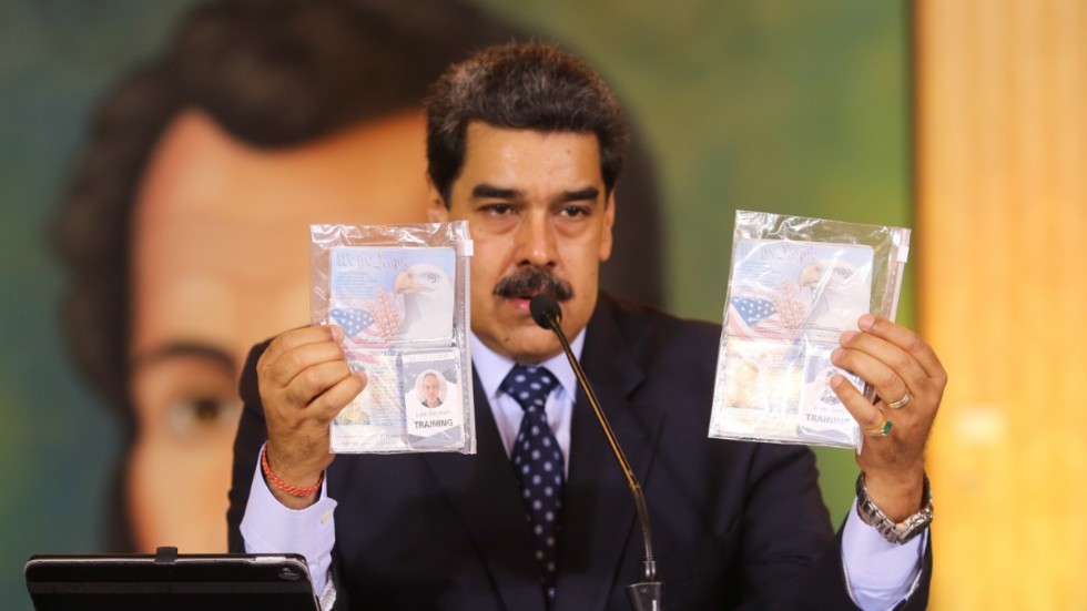 Venezuelas president Nicolás Maduro håller upp två id-handlingar som han hävdar tillhör de två män från USA som gripits för inblandning i det påstådda kuppförsöket.