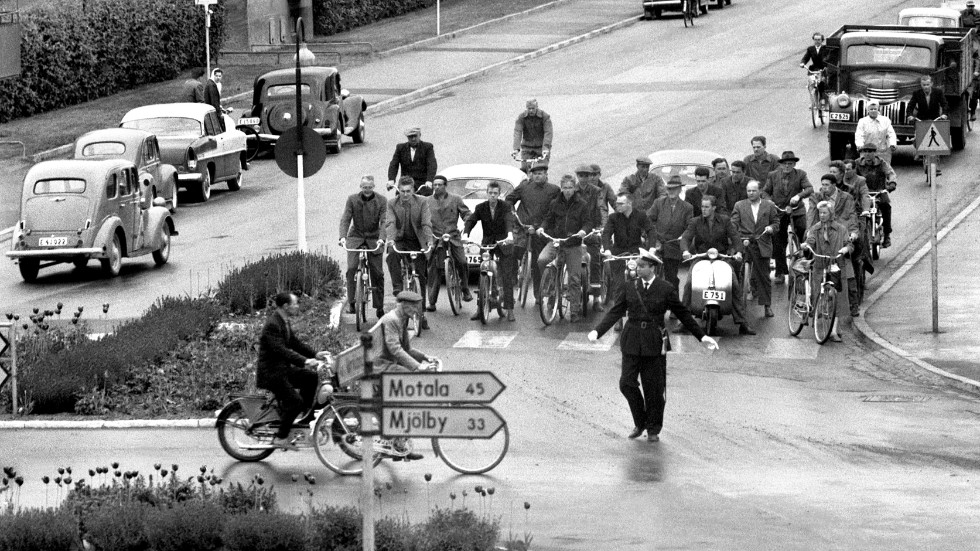 Juni 1958 och ett gäng Saabarbetare passerar Drottningrondellen på väg hem från jobbet.