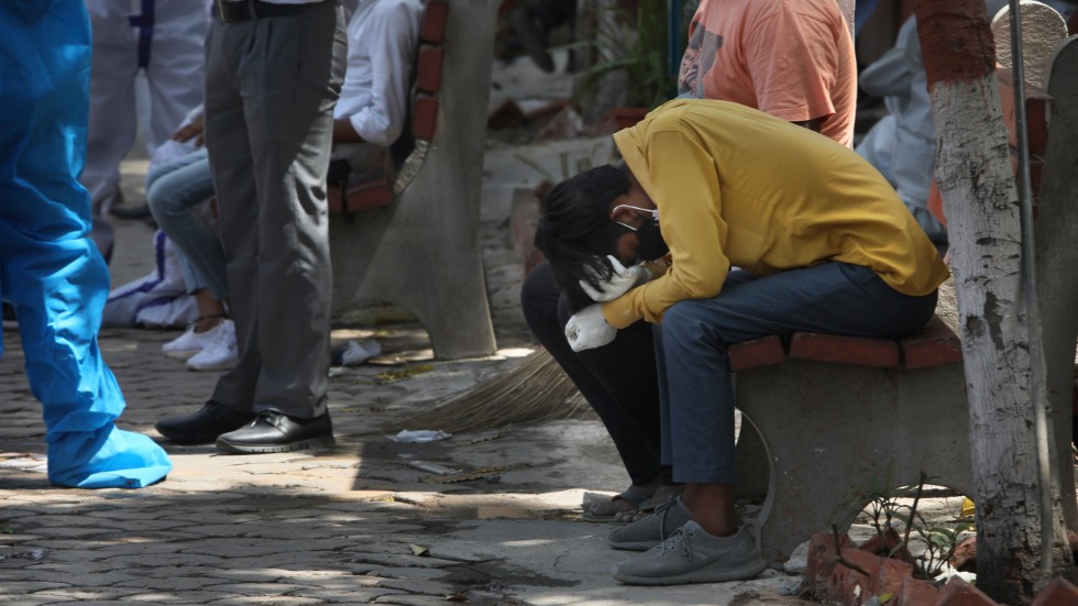 Sörjande anhöriga samlas för kremation av en person som nyligen avlidit i sviterna av covid-19 i Delhi, Indien.