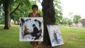 Hon hänger tavlor längs träden i parken: "Ny tradition"