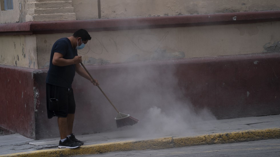 En man sopar upp aska från vulkanen i staden Atlixco efter den senaste veckans utbrott.