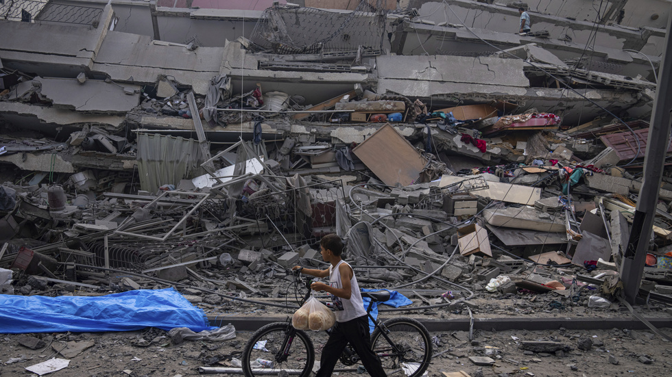 En palestinsk pojke går förbi en sönderbombad byggnad i centrala Gaza med sin cykel.