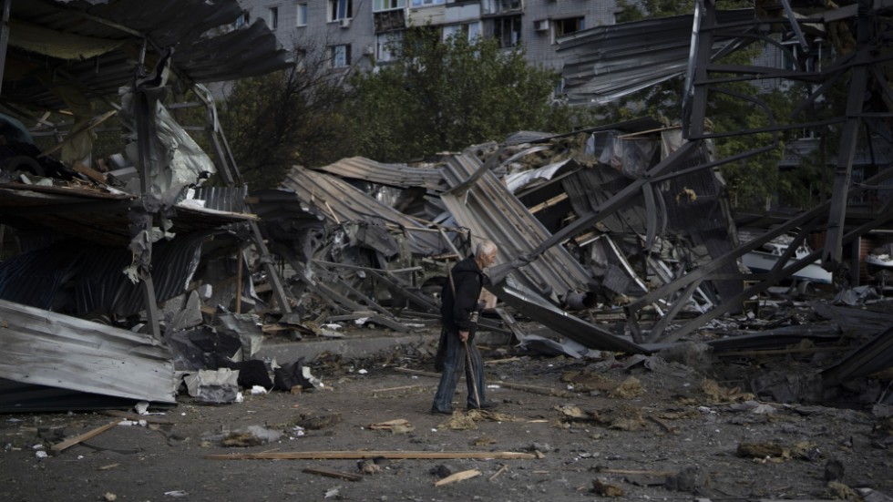 En äldre man går förbi en butik som förstörts i en rysk attack mot Zaporizjzja den 11 oktober.