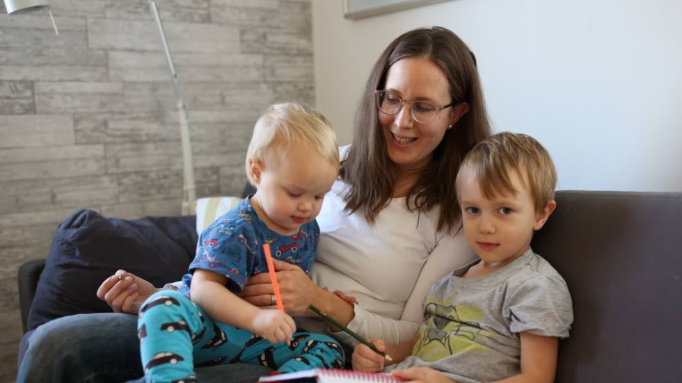 Malin Engvall myser i soffan tillsammans med barnen Albin, fyra år och Sonja, två år