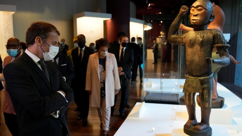 Den franske presidenten Emmanuel Macron betraktar en av de statyer på det etnografiska museet Quai Branly i Paris som Frankrike nu lämnat tillbaka till Benin. Arkivbild.