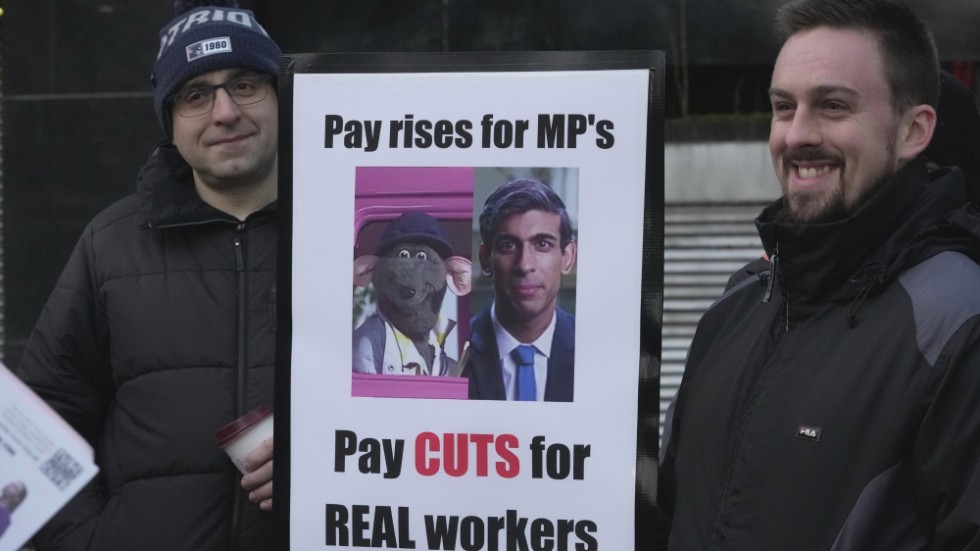 Strejkande lokförare håller upp ett plakat med ett nidporträtt av den brittiske premiärministern Rishi Sunak vid sidan av den brittiska tv-karaktären och dockan Roland Rat.