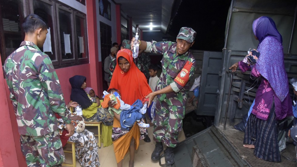 Indonesiska soldater hjälper kvinnor och barn upp på en militärbil efter att de har varit fast till sjöss i flera veckor.