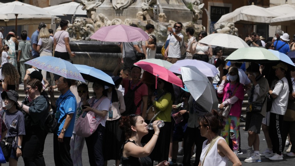 Turister använder paraplyn för att skydda sig mot solen när de köar till Pantheon i Rom den 8 juli.