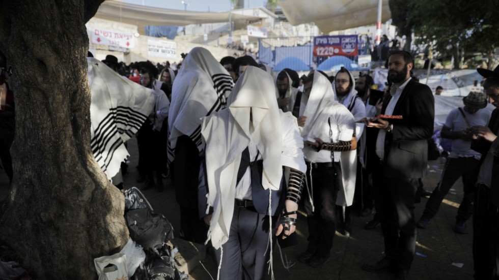 Ultraortodoxa judar ber på fredagsmorgonen nära olycksplatsen vid berget Meron i norra Israel.