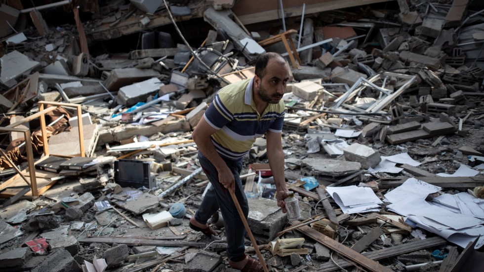 En palestinsk man i resterna av en byggnad som förstördes i en israelisk morgonraid den 18 maj.
