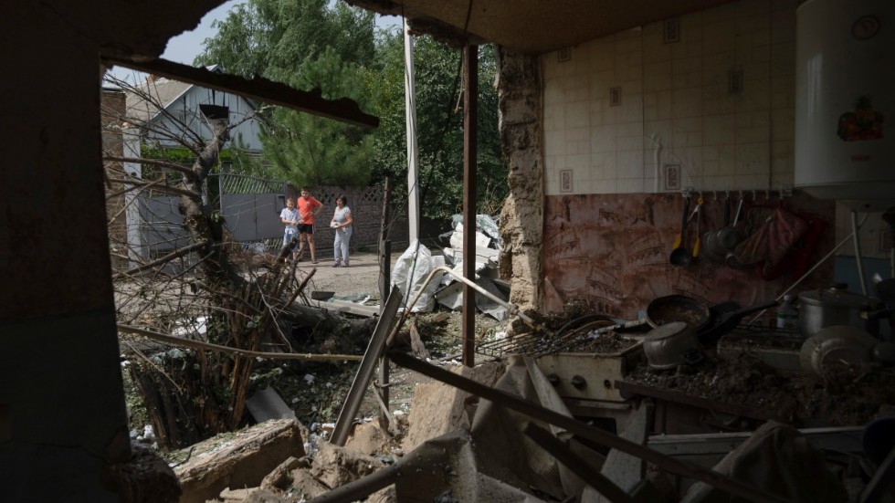 Människor tittar på ett hus i Nikopol i södra Ukraina som bombats av Ryssland. Fotot togs 22 augusti.