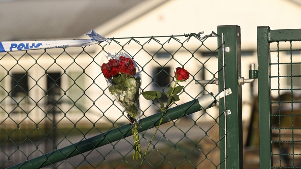 Blommor vid grinden till ett vårdboende i Enköping där en ung kvinna i personalen dödades på torsdagen.