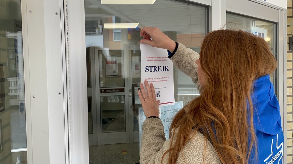 Sofia Andersson, of Vårdförbundet, puts up informational posters on the door to inform patients that a large portion of the staff at Heimdall Health Center is on strike.