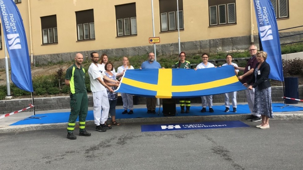 Vårdpersonalen på Skellefteå lasarett tar emot den svenska flaggan som de tilldelades av stiftelsen Sveriges nationaldag.