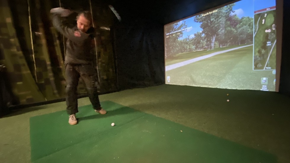 Jakob Riis, som är en av de drivande krafterna bakom Storebro Indoor Golf, svingar klubban vid företagets simulator som nu är igång igen efter den märkliga stölden för ett par veckor sen.