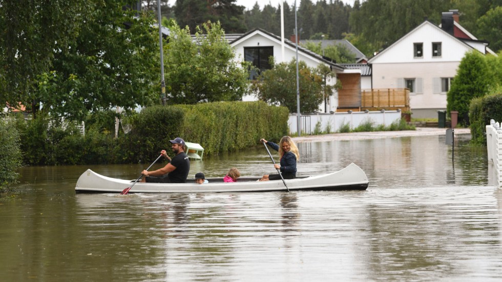 En familj i Gävle paddlar kanot genom ett översvämmat villaområde efter de kraftiga skyfallen. Bild från 18 augusti.