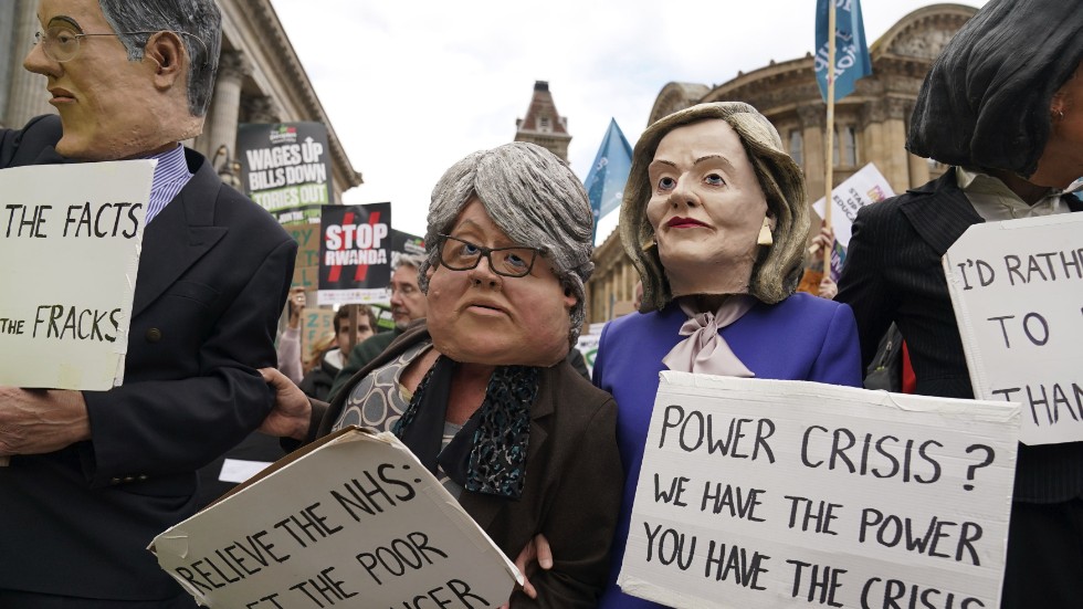 Demonstranter med masker i papier-maché föreställande den brittiska premiärministern Liz Truss till höger, och biträdande premiärminister Therese Coffey till vänster protesterar mot regerings politik utanför regeringspartiet Tories kongress i Birmingham