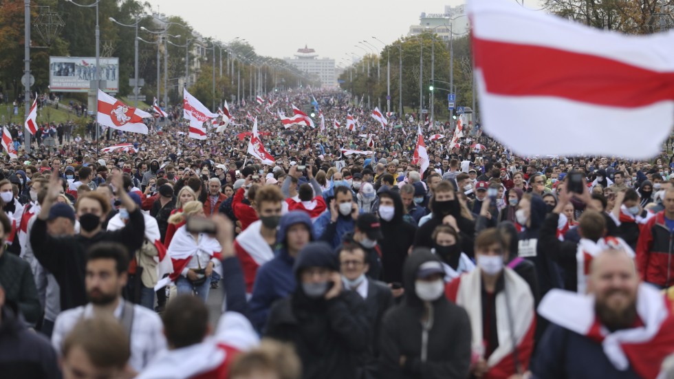 Demonstranter i Minsk viftar med en alternativ belarusisk flagga som ska symbolisera ett demokratiskt Belarus. Hundratusentals människor demonstrerade i Belarus 2020, men regimen slog ned missnöjet med rysk hjälp. Arkivbild.