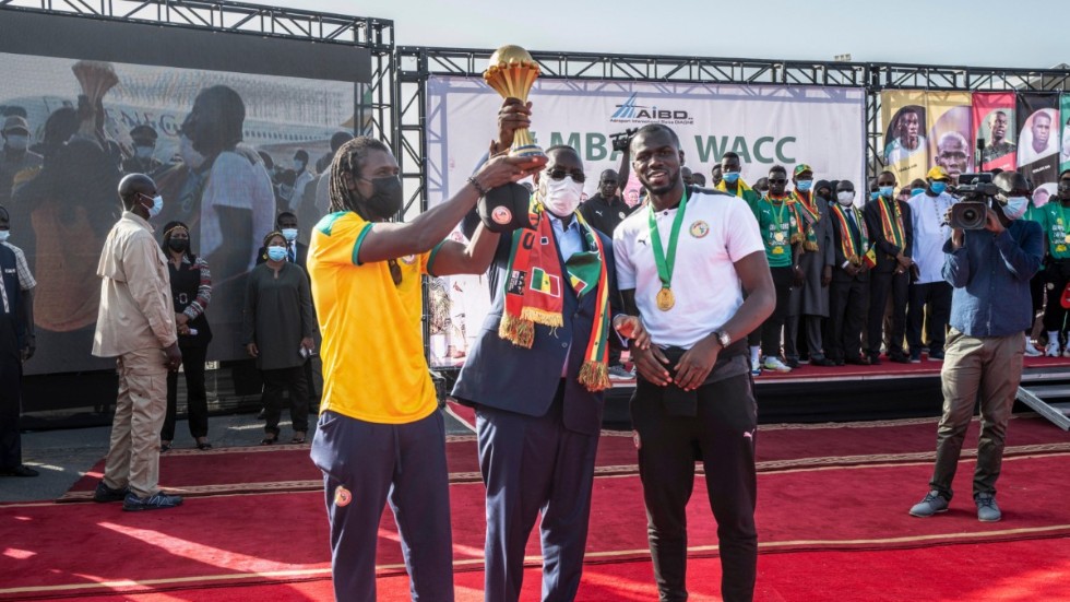 Förbundskapten Aliou Cissé, president Macky Sall och lagkaptenen Kalidou Koulibaly poserar med pokalen.