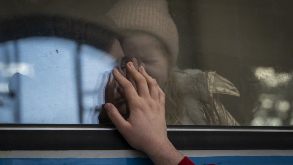 Ukrainska flyktingar, på ett tåg med destination Polen, tar farväl av en manlig familjemedlem. Bilden är från tågstationen i Lviv i västra Ukraina i mars i fjol.