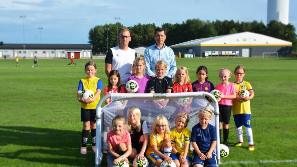David Lindgren från Vimmerby IF och Stig Bäck från Sparbanksstiftelsen Vimmerby, står vid det nya "tre mot tre"-målet med de sjuåriga tjejerna som tränade för fullt.