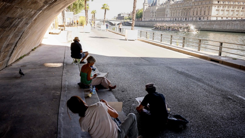 En grupp människor söker skugga under en bro vid floden Seine i Paris. Arkivbild