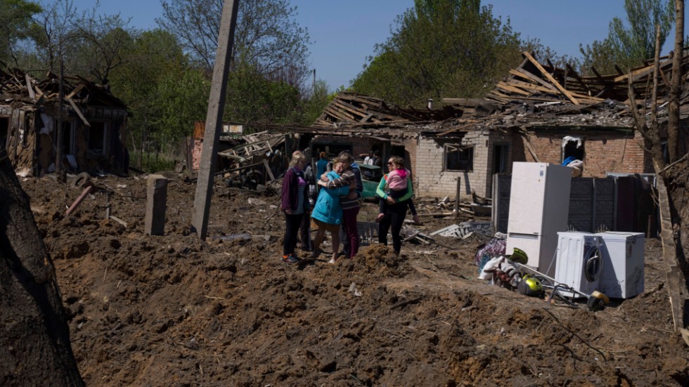 Människor håller om varandra intill en stor krater i ett bostadsområde i Bachmut, Donetsk, som bombats i ett ryskt flyganfall. Bilden togs på lördagen.