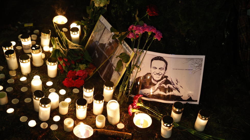 Människor tände ljus vid ett porträtt av Aleksej Navalnyj utanför ryska ambassaden i Stockholm. 