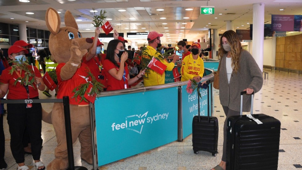 Passagerare välkomnas när de anländer till flygplatsen i Sydney, när landet efter 100 veckor öppnar för turister igen.