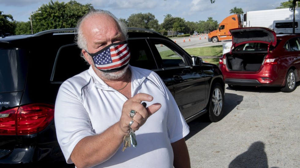 Arbetslöse Roy Schimmel väntar på en matlåda vid sin bil vid ett utskänkningsställe i Sunrise i Florida.