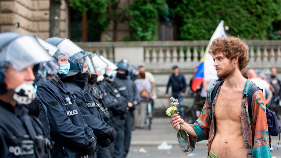 En protestdeltagare håller fram blommor mot poliser vid en demonstration i Berlin i slutet av augusti.