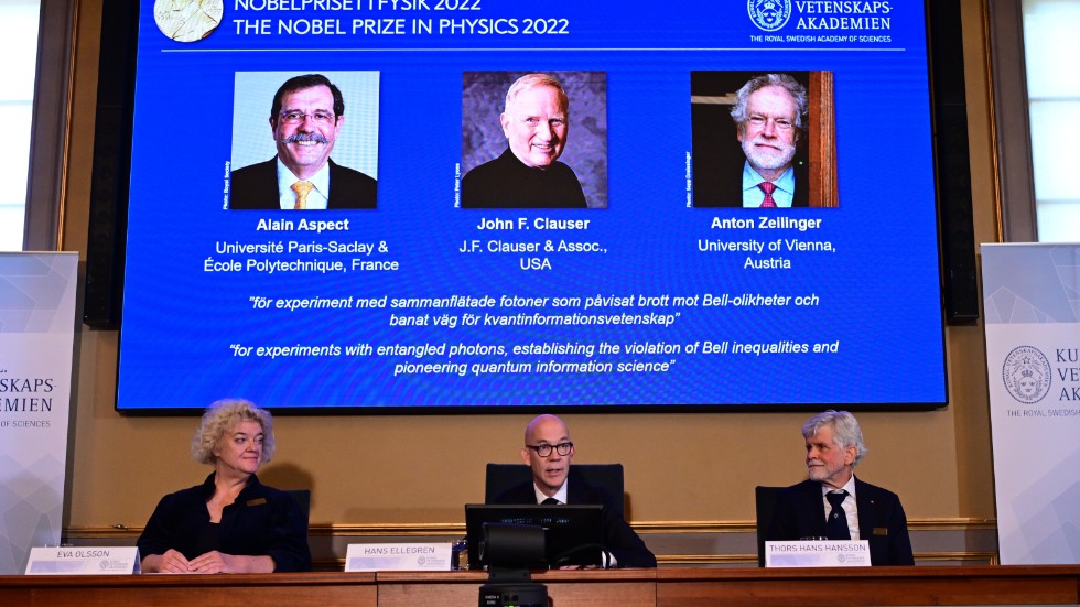 Hans Ellegren (mitten), Vetenskapsakademiens ständige sekreterare, tillkännager vinnarna av 2022 års Nobelpris i fysik: Alain Aspect, John F Clauser och Anton Zeilinger. Till vänster sitter professor Eva Olsson och till höger professor Thors Hans Hansson.
